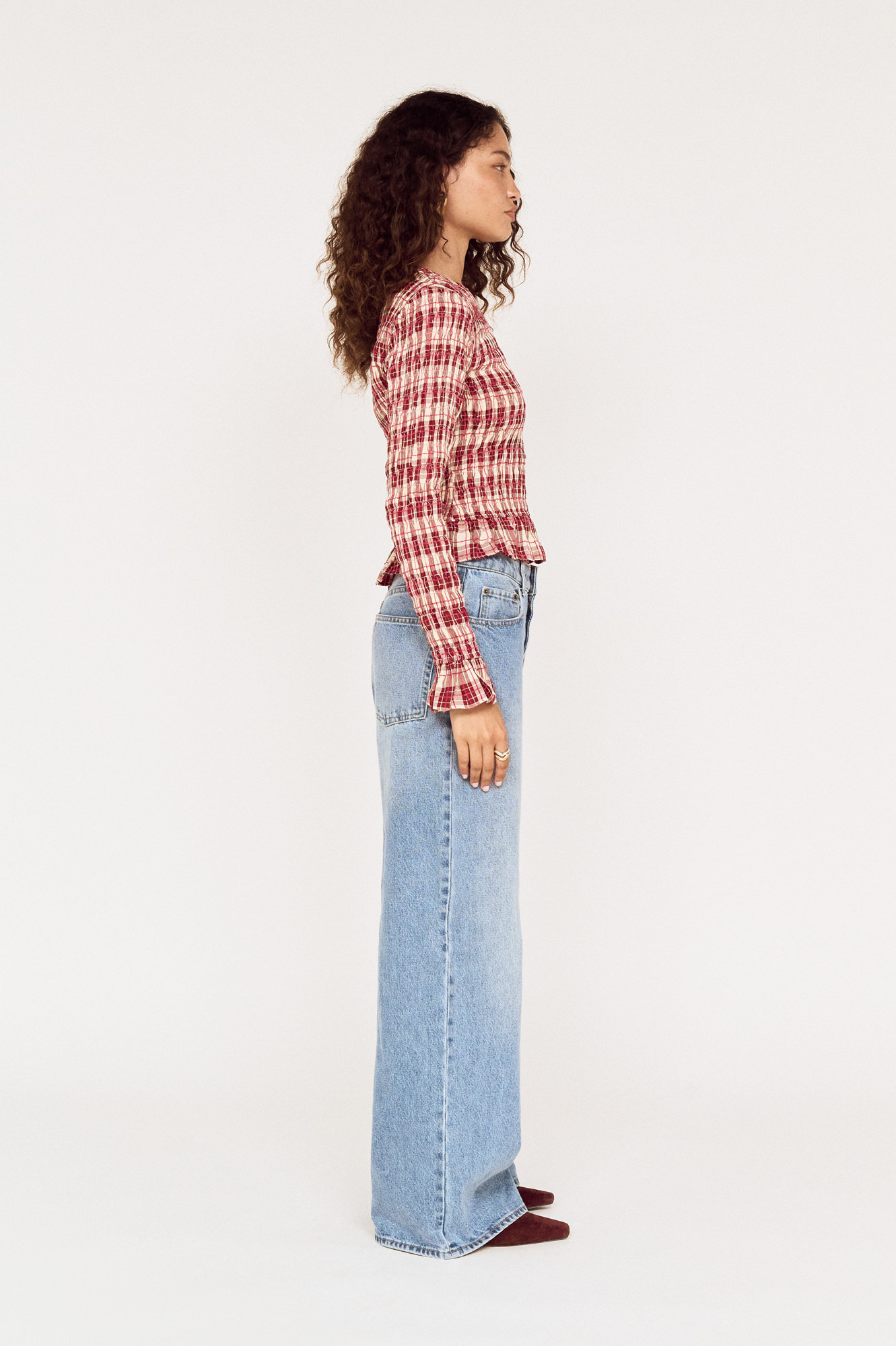 Side view of a model wearing a MINKPINK red check top with wide-leg jeans photographed for fashion e-commerce by Shoot.Studio in Sydney.