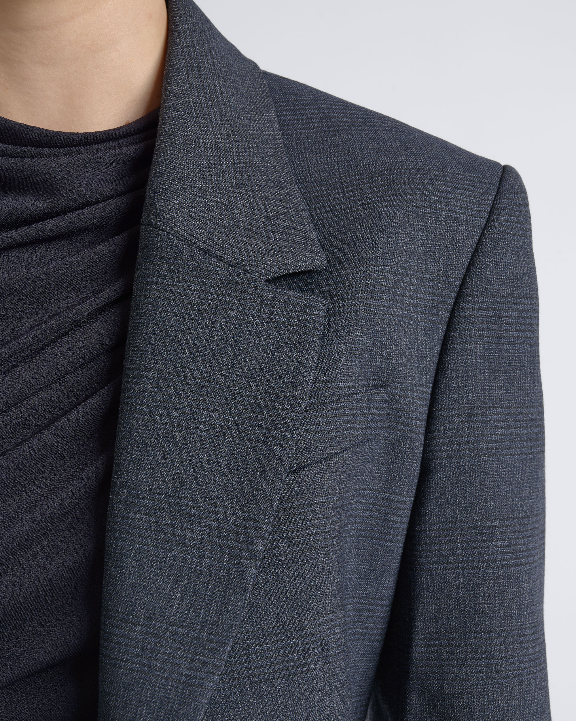Close-up of a CUE charcoal blazer layered over a dark top.