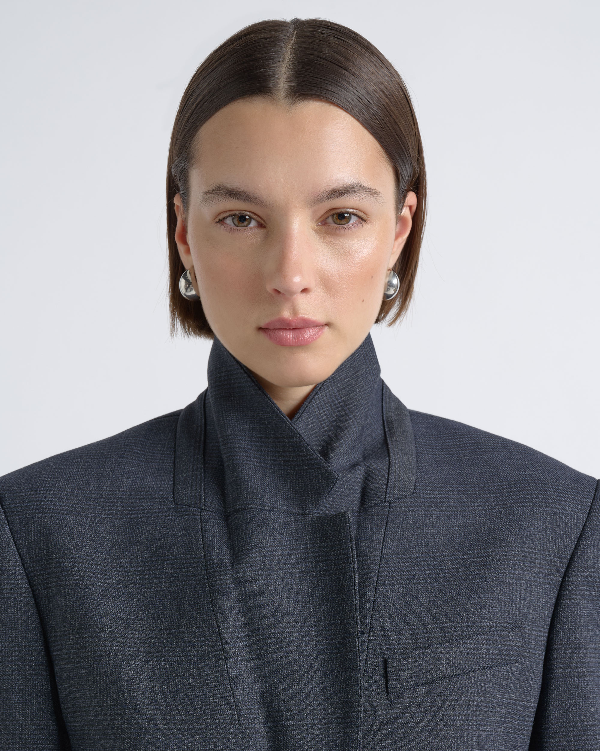 Close portrait of a model wearing a high-collar CUE charcoal blazer.