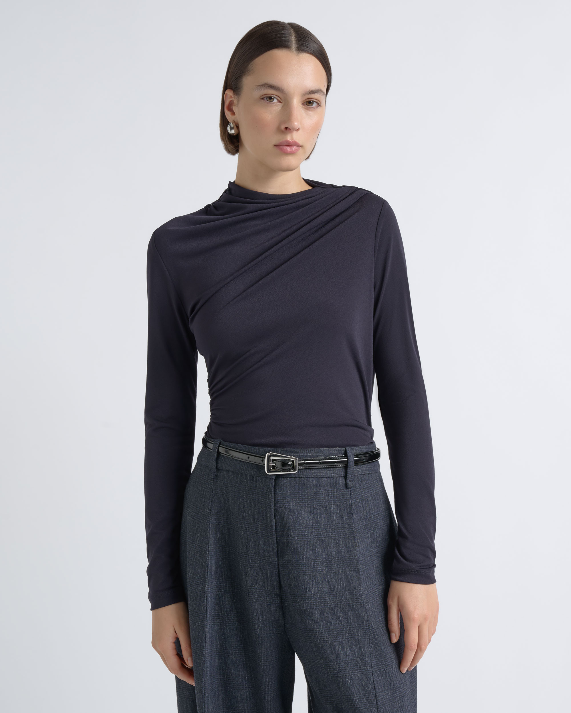 Portrait of a model wearing a CUE charcoal top with wide-leg trousers.