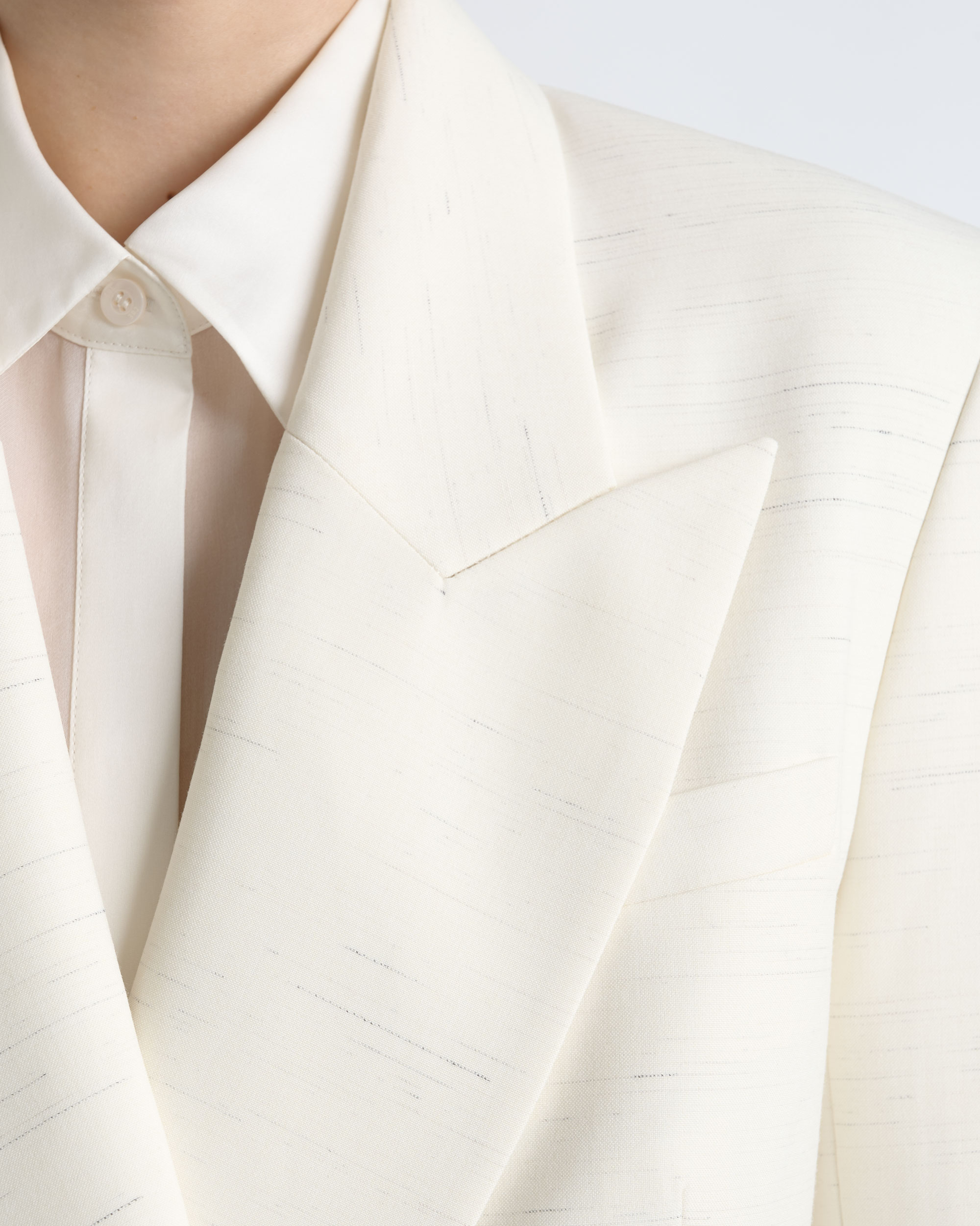 Close-up of the lapel and pocket on a CUE ivory blazer.