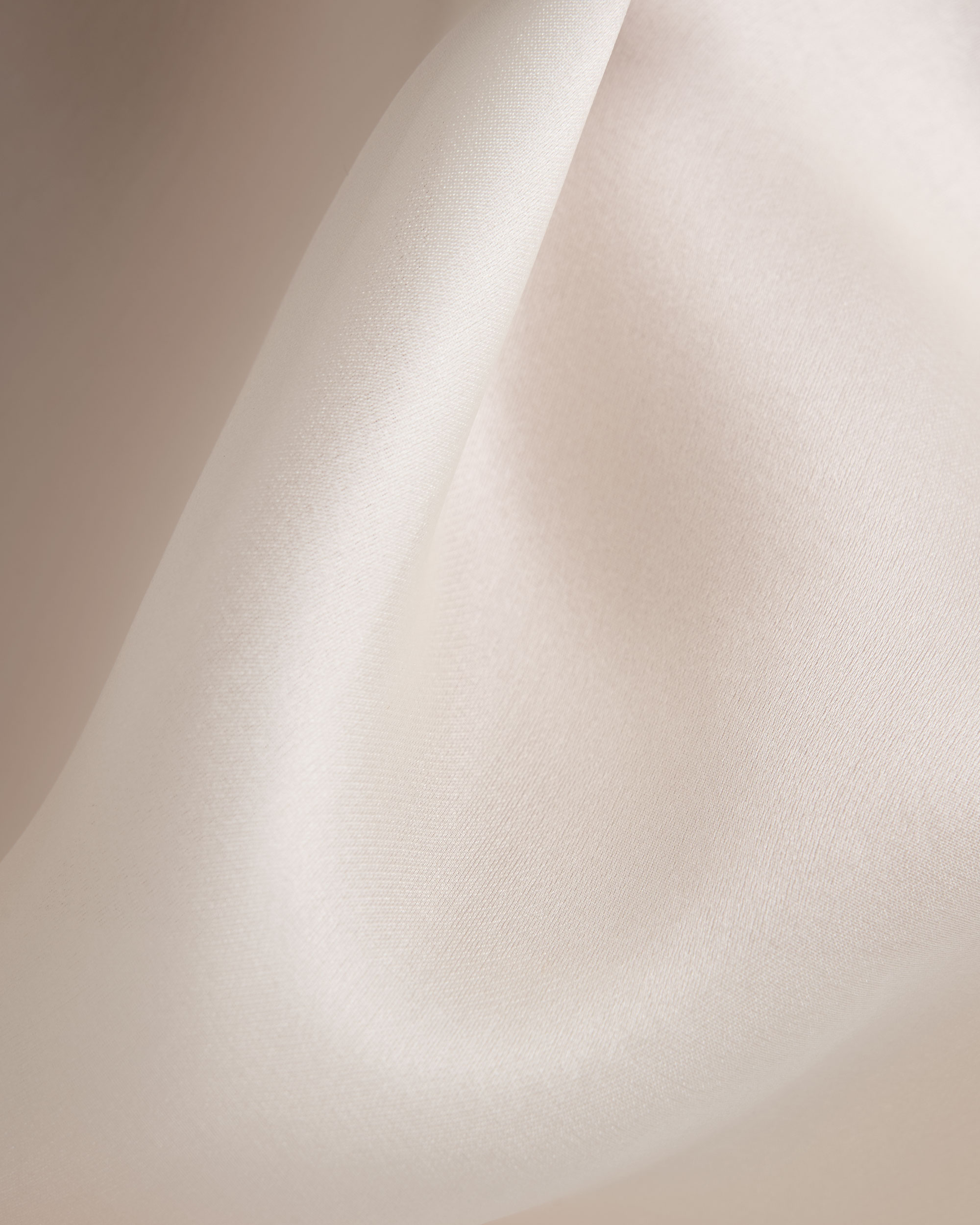 Close-up of softly draped ivory fabric from a CUE garment.