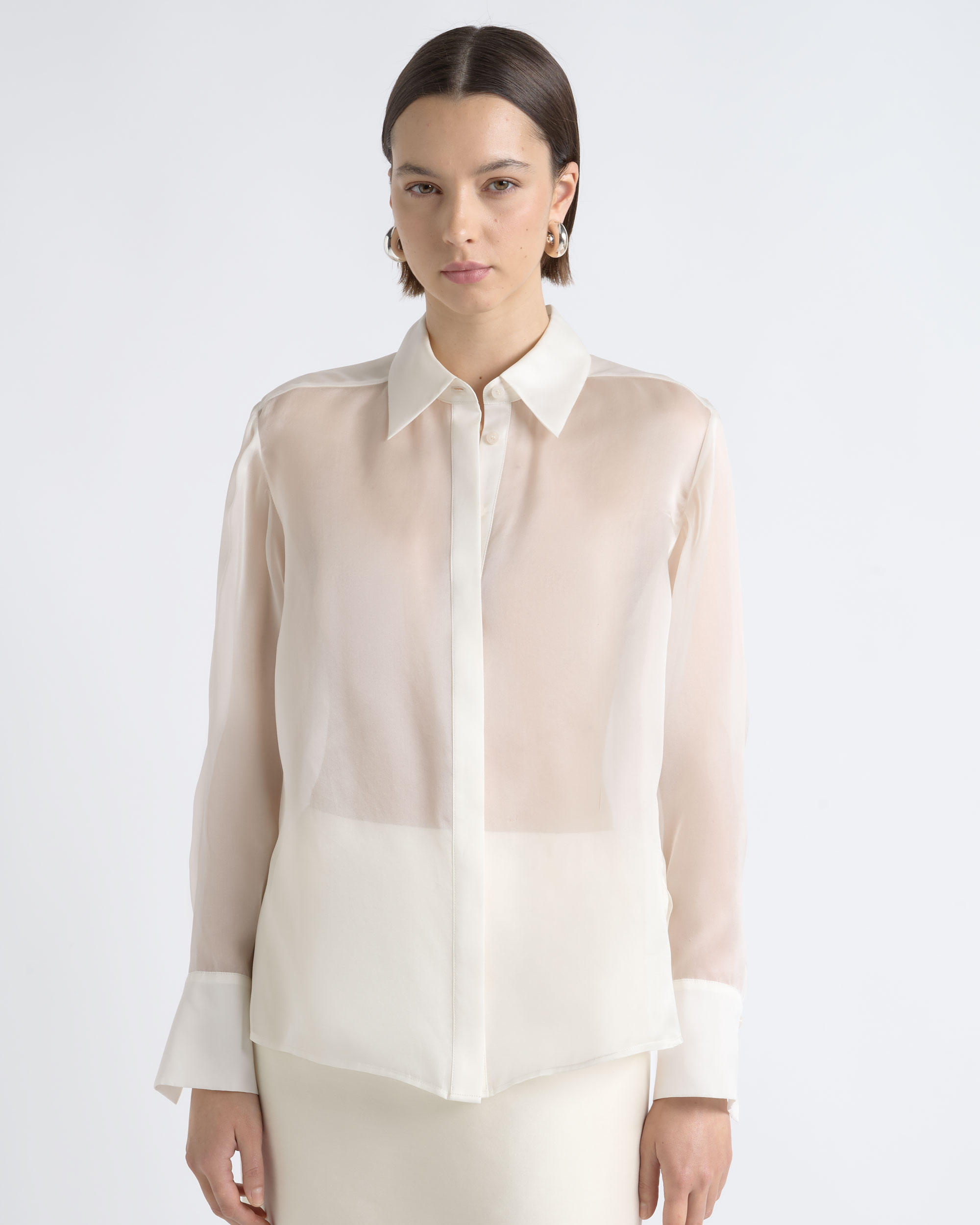 Front view of a model wearing a CUE ivory sheer button-up shirt and trousers.