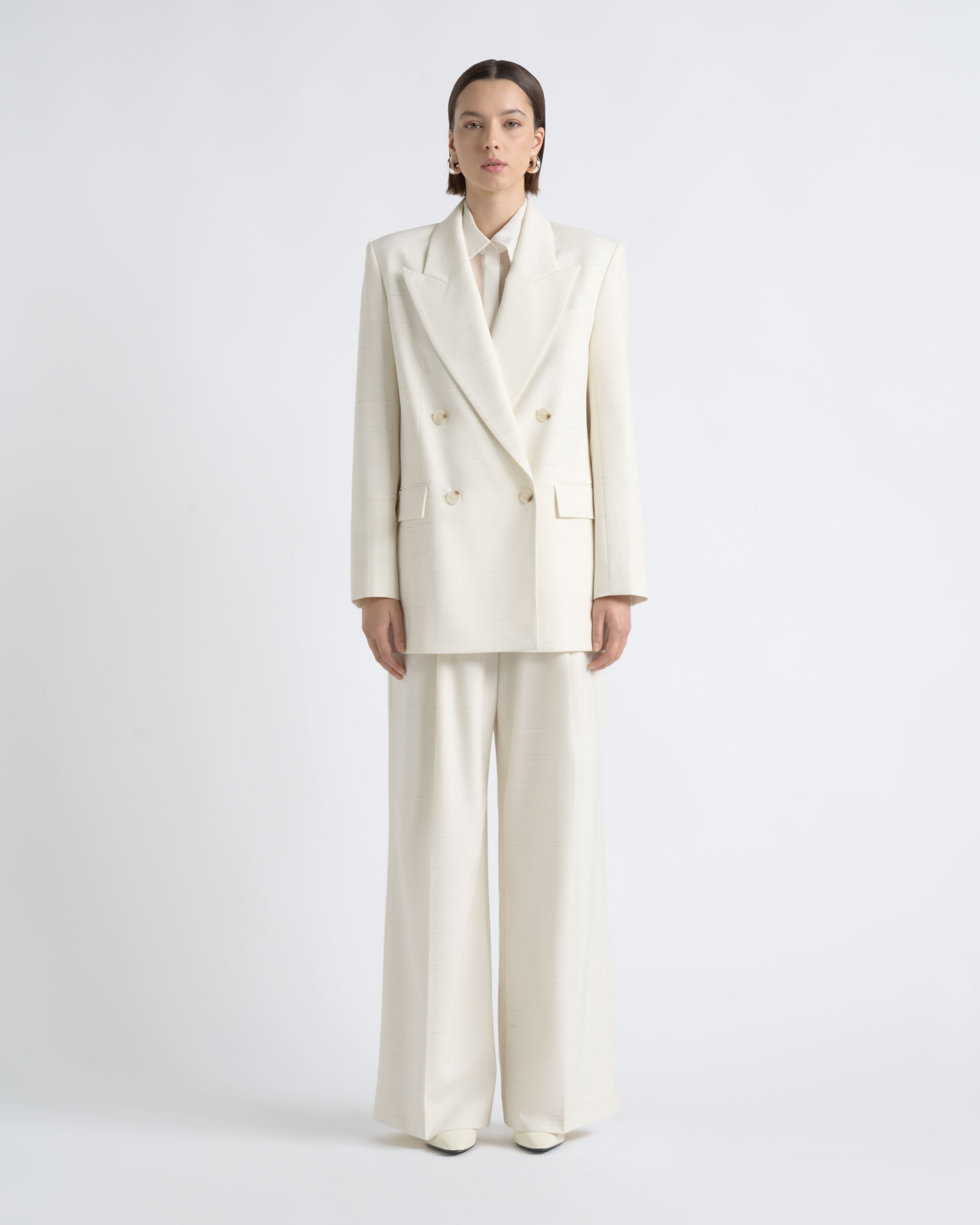 Front view of a model wearing a CUE ivory blazer and wide-leg trousers.
