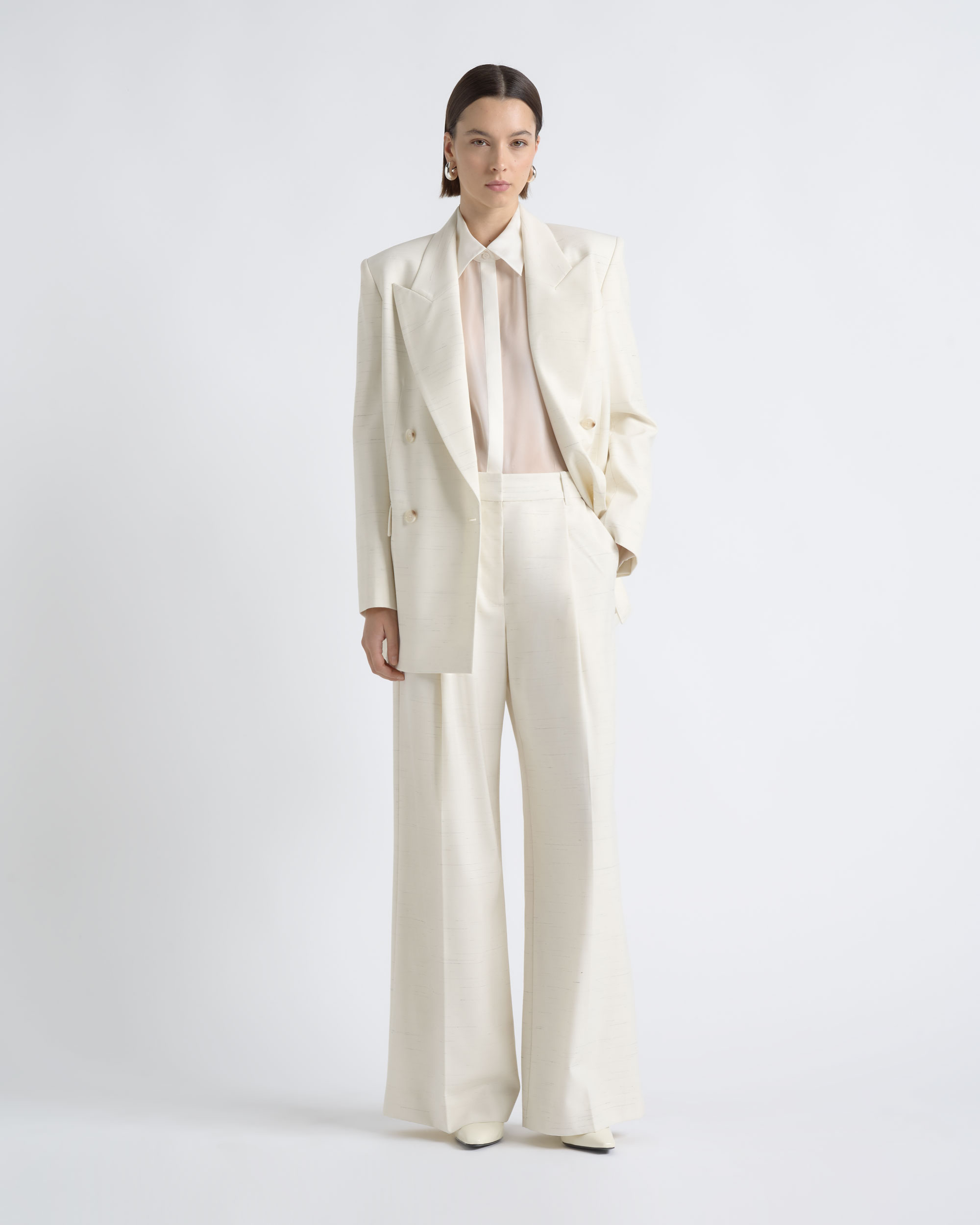 Full-length view of a model wearing an open CUE ivory blazer with wide-leg trousers.
