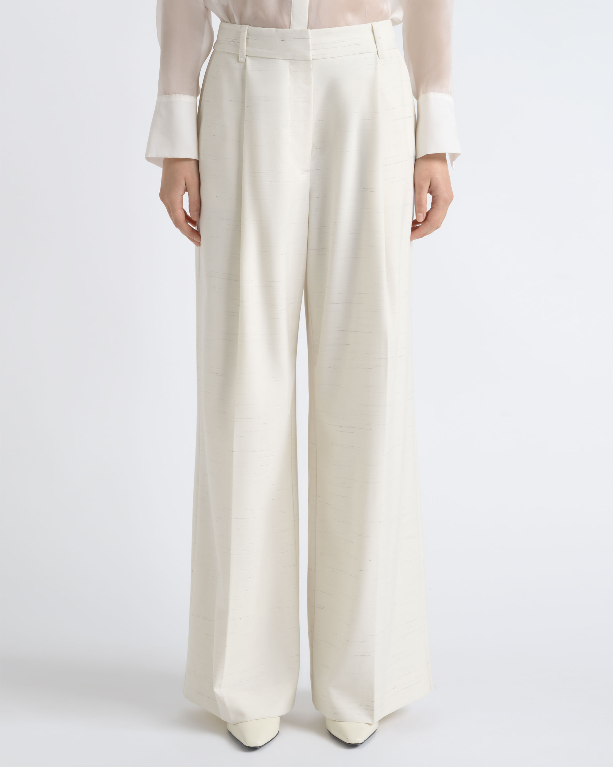 Close-up of ivory wide-leg trousers worn by a model for CUE.