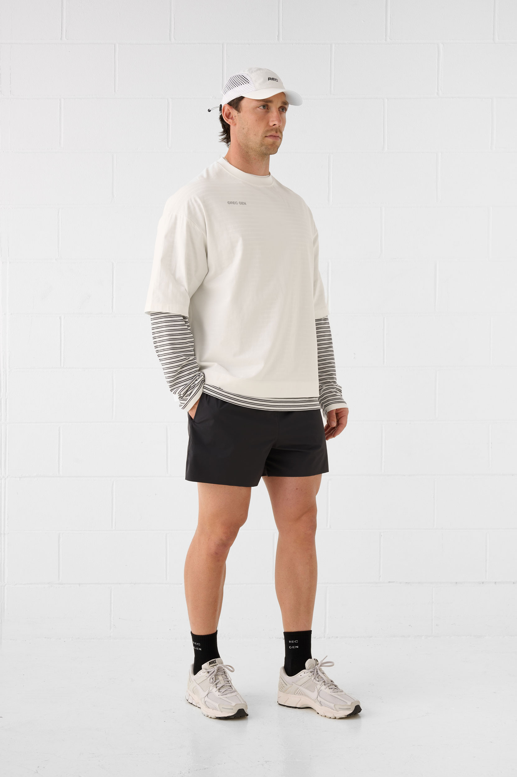REC GEN men's layered off-white top and black shorts, full-length side view